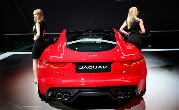 Models stand next to Jaguar F Type sports car on display on turntable at New York International Auto Show in New York City