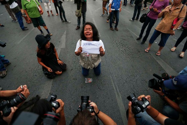 Reporteros toman fotografías de un manifestante contra el gobierno militar con un cartel en el Monumento a la Victoria en Bangkok / Damir Sagolj / Reuters