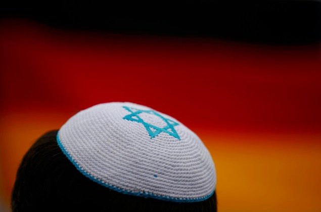 A man wearing a kippah listens to speakers during anti-Semitism demo at Berlin's Brandenburg Gate