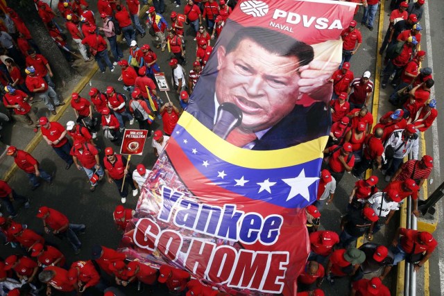 Workers of state-run oil company PDVSA hold a giant picture of Venezuela's late president Hugo Chavez during a rally against imperialism in Caracas