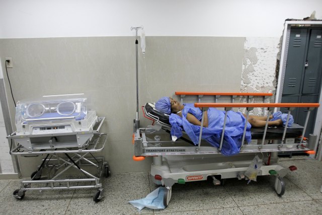 A pregnant woman lays on a bed without sheets as she recovers after labour at a maternity hospital in Maracaibo, Venezuela