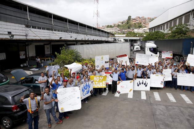 Empresas Polar workers hold placards and shout in a facility used by the company as a distribution center, during the occupation of its installations by government representatives in Caracas July 30, 2015. REUTERS/Carlos Garcia Rawlins
