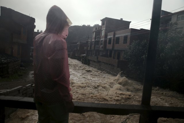 A man watches floodwaters in a heavy rain at a town hit by Typhoon Soudelor in Ningde, Fujian province