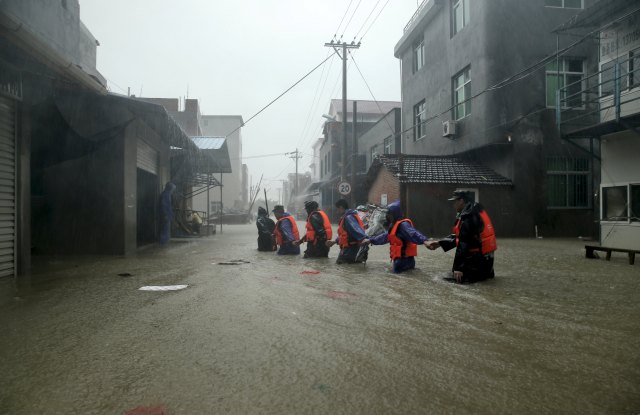Rescue workers walk on a flooded street at a town hit by Typhoon Soudelor in Ningde, Fujian province, China, August 9, 2015. Typhoon Soudelor landed on the coast of Putian City in southeast China's Fujian Province late Saturday after lashing Taiwan, bringing strong winds and downpours and causing power outages in the province and neighboring Zhejiang, state media CCTV reported. REUTERS/Stringer CHINA OUT. NO COMMERCIAL OR EDITORIAL SALES IN CHINA