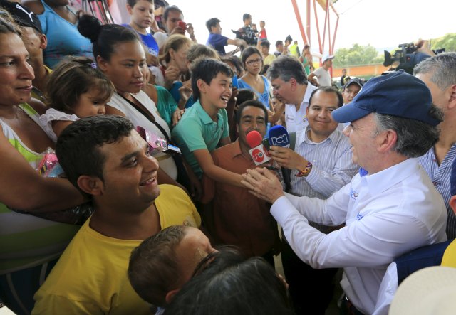 Colombia's President Juan Manuel Santos greets people deported from Venezuela during a visit at a temporary shelter in Villa del Rosario