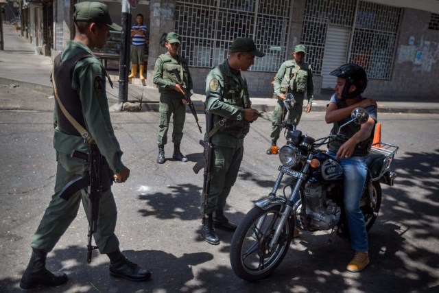 CAR12. SAN ANTONIO (VENEZUELA), 30/08/2015.- Integrante del ejército venezolano inspeccionan a un motociclista en las inmediaciones de la Aduana Principal fronteriza entre Colombia y Venezuela hoy, domingo 30 de agosto de 2015, en la ciudad de San Antonio (Venezuela). El Gobierno de Venezuela reiteró hoy que el cierre de parte de la frontera solo ha generado beneficios a su país después de que las autoridades hicieran un recorrido para confirmar que la medida se está cumpliendo en 140 kilómetros de los límites con Colombia. El presidente de Venezuela Nicolás Maduro decidió cerrar parte de la frontera con Colombia la medianoche del 19 de agosto después de que tres militares y un civil venezolanos resultasen heridos en un ataque de supuestos contrabandistas en la zona limítrofe a lo que sumó, dos días después, el decreto de estado de excepción en la zona. EFE/MIGUEL GUTIÉRREZ