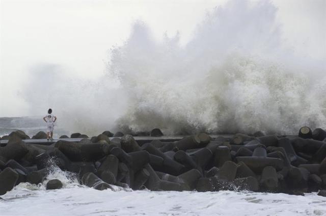 Un surfista observa grandes olas golpeando el rompeolas en Isumi, en la prefectura de Chiba en Japón, hoy, 9 de septiembre de 2015. Las autoridades locales recomendaron hoy la evacuación de unas 73.000 personas en la localidad costera de Hamamatsu, en la prefectura de Shizuoka (centro), por las fuertes lluvias que arrastra el tifón Etau en su camino hacia Japón. EFE/Everett Kennedy Brown