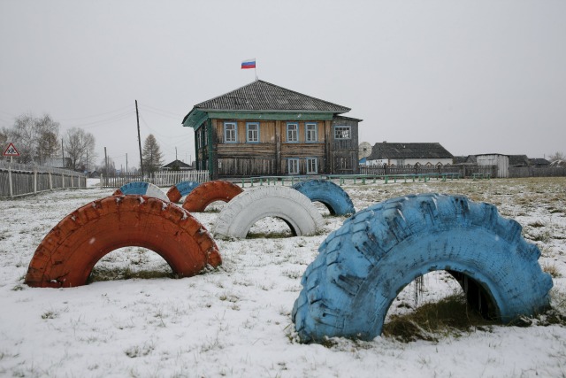 Neumáticos de coches pintados con los colores de la bandera rusa de pie en frente del edificio de la administración en Sankin, región de Sverdlovsk, Rusia 17 de octubre de 2015. En un rincón remoto de la región de los Urales en el extremo de un ferrocarril de vía estrecha es Kalach, población alrededor de una docena. Hace tres décadas 600 personas llamaron a la casa del pueblo, pero la industria forestal local sufrieron como la antigua Unión Soviética implosionó y la gente se alejó en busca de trabajo. En Kalach hoy no hay teléfonos, no hay recepción móvil y sólo unas pocas horas de electricidad al día. REUTERS / Maxim Zmeyev