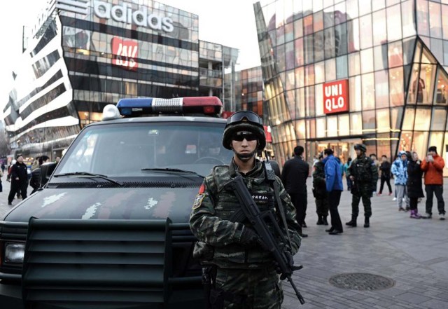 An armed Chinese policeman stands guard in the popular shopping and nightlife area of Sanlitun in Beijing on December 24, 2015. Foreign embassies in China issued a warning on December 24 about possible threats against "Westerners" in a popular Beijing neighbourhood ahead of the Christmas holiday. AFP PHOTO/GOH CHAI HIN / AFP / GOH CHAI HIN