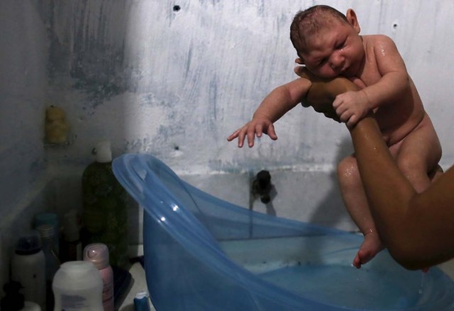 Daniele Santos, 29, holds her son Juan Pedro who is 2-months-old and born with microcephaly, after bathing him at their house in Recife, Brazil, February 9, 2016. The Zika virus may be particularly adept at entrenching itself in parts of the body that are shielded from the immune system, making it harder to fight off and possibly lengthening the timeframe in which it can be transmitted, top U.S. experts said on Friday. Picture taken February 9, 2016.  REUTERS/Nacho Doce
