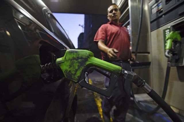 A worker puts gas to a vehicle in Caracas on February 17, 2016. Venezuela's President Nicolas Maduro said Wednesday he would raise the price of gasoline for the first time in 20 years, as he faces growing pressure to ease an economic crisis. Maduro said in a televised address he would raise the pump price of premium gasoline from its current super-low level of $0.01 to the equivalent of $0.95 at the fixed official exchange rate, in a country where citizens are struggling with soaring inflation. AFP  PHOTO/JUAN BARRETO / AFP / JUAN BARRETO