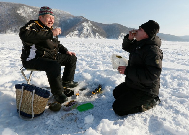 Los hombres beben whisky mientras que la pesca en el río Yenisei cubierta de hielo en el distrito de Taiga fuera de Krasnoyarsk, Siberia, Rusia, 22 de febrero de 2016. REUTERS / Ilya Naymushin