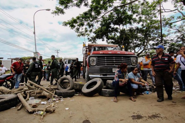 People, including relatives and friends of 28 miners who went missing last week and are feared killed in an attack, block a key highway connecting Venezuela and Brazil in the town of Tumeremo, in the Venezuelan state of Bolivar, to demand answers on what happened to their loved ones, on March 8, 2016. The miners failed to return home from work after their shifts on March 3, and stories soon began circulating that a group of gunmen had attacked the goldmine in southeastern Venezuela where they worked.   AFP PHOTO / WILLIAM URDANETA / AFP / WILLIAM URDANETA