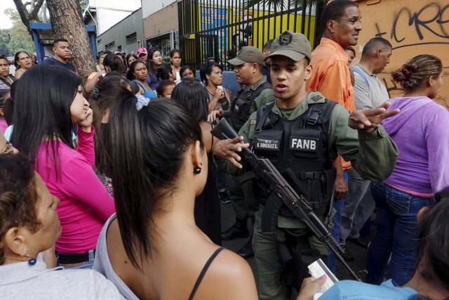 Venezuelan soldiers speak to the crowd as they queue to try and buy cornmeal flour at a supermarket in Caracas March 15, 2016. REUTERS/Carlos Garcia Rawlins