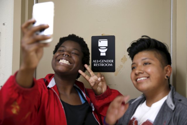 Kween Robinson, 17, (L) and Alonzo Hernandez, 16, pose for a selfie in front of the first gender-neutral restroom in the Los Angeles school district, which they helped lobby for, at Santee Education Complex high school in Los Angeles, California, U.S., April 18, 2016. REUTERS/Lucy Nicholson