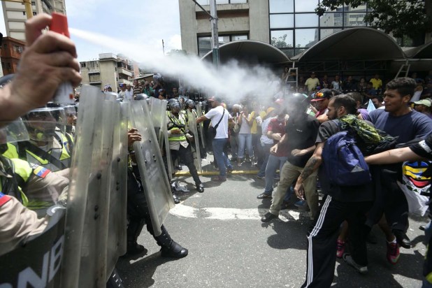 People clash with police as they protest against new emergency powers decreed this week by President Nicolas Maduro in Caracas on May 18, 2016.  Public outrage was expected to spill onto the streets of Venezuela Wednesday, with planned nationwide protests marking a new low point in Maduro's unpopular rule. / AFP PHOTO / JUAN BARRETO