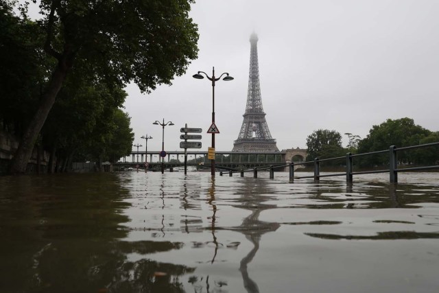 A picture taken on June 2, 2016 shows the river Seine bursting its banks next to the Eiffel Tower in Paris. Officials were putting up emergency flood barriers on June 2 along the swollen river Seine after days of torrential rain -- including near the Louvre, home to priceless works of art.  AFP PHOTO / KENZO TRIBOUILLARD / AFP PHOTO / KENZO TRIBOUILLARD