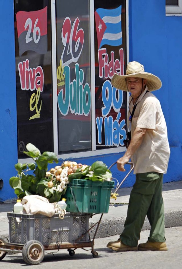 HAB101. LA HABANA (CUBA), 09/08/2016.- Un hombre camina vendiendo cebolla hoy, martes 09 de agosto del 2016, en La Habana (Cuba), junto a un mensaje alusivo al cumpleaños 90 del líder de la revolución cubana Fidel Castro este próximo sábado 13 de agosto. EFE/Ernesto Mastrascusa