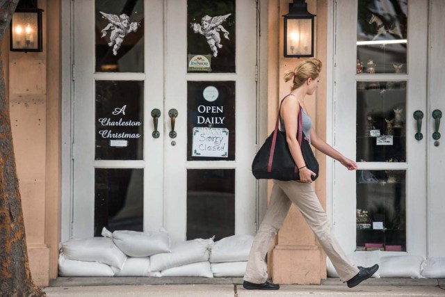 SRX01. CHARLESTON (EE.UU.), 05/10/2016.- Una mujer pasa frente a un restaurante cerrado y con bolsas de arena en las puertas hoy, miércoles 5 de octubre de 2016, como preparativos para el paso del huracán Matthew en Charleston (EE.UU.). EFE/SEAN RAYFORD