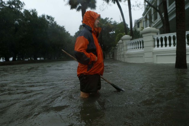 CHARLESTON, SC - OCTOBER 8: A resident makes his way into flooded E. Battery Street with a rake to clear debris from clogged gutters in the wake of Hurricane Matthew on October 8, 2016 in Charleston, South Carolina. Across the Southeast, Over 1.4 million people have lost power due to Hurricane Matthew which has been downgraded to a category 1 hurricane on Saturday morning. Brian Blanco/Getty Images/AFP