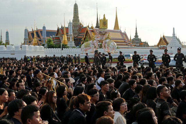 Mourners kneel as a motorcade carrying the body of Thailand's late King Bhumibol Adulyadej drives past, in front of the Grand Palace in Bangkok, Thailand October 14, 2016. REUTERS/Jorge Silva