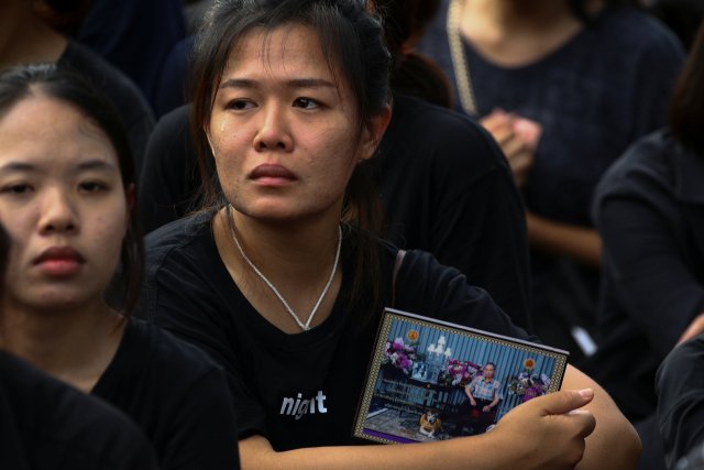 A mourner cries while holding a picture of Thailand's late King Bhumibol Adulyadej in Bangkok, Thailand, October 14, 2016. REUTERS/Athit Perawongmetha