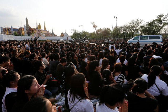 Mourners kneel as a motorcade carrying the body of Thailand's King Bhumibol Adulyadej drives past in front of the Grand Palace in Bangkok, Thailand October 14, 2016. REUTERS/Jorge Silva