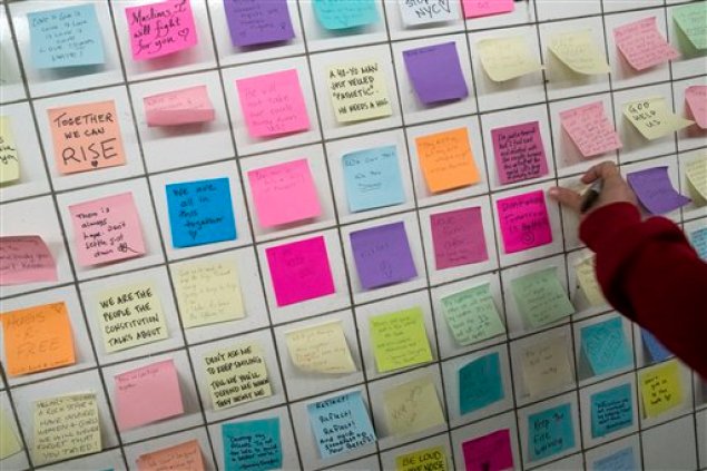 Un viajero coloca una noa con un mensaje en el muro de la "Subway Therapy", el 11 de noviembre de 2016, en Nueva York. Matthew Chavez, que responde al nombre artístico de Levee, comenzó la instalación en un tunel subterráneo que conecta la línea 1 con la L en la calle 14. En ella anima a los usuarios del servicio a dejar sus sentimientos sobre las elecciones presidenciales escritos en Post-It. (AP Foto/Mary Altaffer)