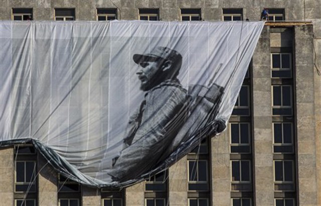 Varios hombres colocan un gran cartel con la imagen del fallecido líder cubano Fidel Castro como un joven revolucionario  desde el edificio de la Biblioteca Nacional de Cuba en La Habana, Cuba, el domingo 27 de noviembre de 2016. (AP Foto/Desmond Boylan)