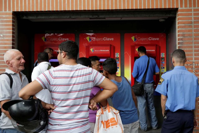 People line up to withdraw cash from an automated teller machine (ATM) outside a Banco de Venezuela branch in Caracas, Venezuela November 25, 2016. Picture taken November 25, 2016. REUTERS/Marco Bello