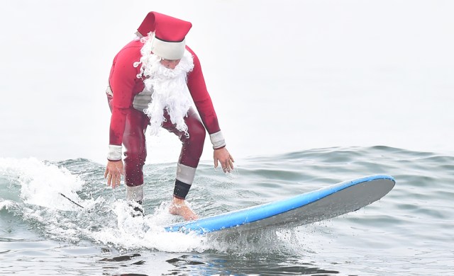 Surfing Santa, Michael Pless, surfs at Seal Beach, California on December 10, 2016, where he runs a surfing school and has every December since in 1990's gone out to surf in his Santa Claus outfit. / AFP PHOTO / Frederic J. BROWN