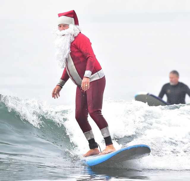 Surfing Santa, Michael Pless, surfs at Seal Beach, California on December 10, 2016, where he runs a surfing school and has every December since in 1990's gone out to surf in his Santa Claus outfit. / AFP PHOTO / Frederic J. BROWN
