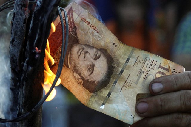 A man burns a 100-bolivar bill during a protest in El Pinal, Venezuela December 16, 2016. REUTERS/Carlos Eduardo Ramirez