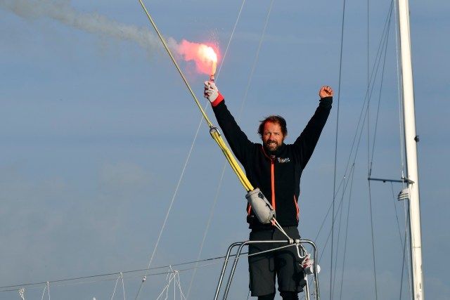 French skipper Thomas Coville holds a burning flare onboard his "Sodebo Ultim'" multihull as he arrives in the port of Brest, western France, on December 26, 2016, after beating the record in solo non-stop round the world sailing. Coville, 48, slashed eight days off the record when he ended an astonishing solo non-stop circumnavigation of the World on his 31m maxi trimaran on December 25, 2016, in just 49 days, 3 hours, 7mins and 38secs. / AFP PHOTO / Damien MEYER