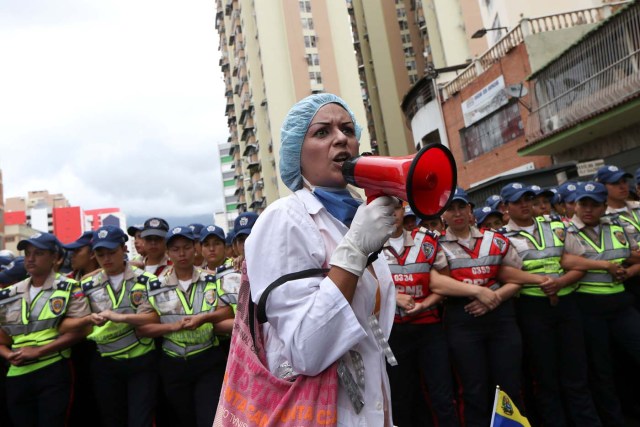 A woman shouts slogans in front of the riot police during a rally of workers of the health sector and opposition supporters, due to the shortages of basic medical supplies and against Venezuelan President Nicolas Maduro's government in Caracas, Venezuela February 7, 2017. REUTERS/Carlos Garcia Rawlins