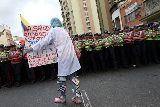 A woman holds a placard in front of the riot polices during a rally of workers of the health sector and opposition supporters, due to the shortages of basic medical supplies and against Venezuelan President Nicolas Maduro's government in Caracas, Venezuela February 7, 2017. The placard reads, "Help us, the patients are dying". REUTERS/Carlos Garcia Rawlins