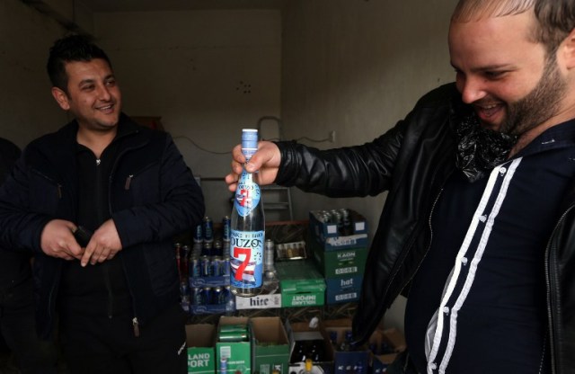 An Iraqi man buys alcohol from the alcohol shop of Wissam Ghanem, an Iraqi man from the Yazidi community, in the Iraqi town of Bashiqa some 20 kilometres north east of Mosul on February 17, 2017. Ghanem, who returned to the town of Bashiqa after Kurdish Peshmerga forces retook the town from Islamic State (IS) group jihadists, re-opened his alcohol business which was strictly forbidden under the rule of the Islamists, after finding cans of beer and bottles of spirits in abandoned houses formerly occupied by IS fighters. / AFP PHOTO / SAFIN HAMED