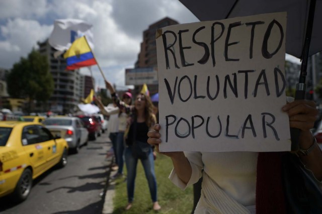 Supporters of Ecuadorean presidential candidate for the CREO party Guillermo Lasso, protest with a sign reading "Respect popular will" outside the National Electoral Council in Quito on February 20, 2017, as they wait for the final results of Sunday's presidential election. Leftist Lenin Moreno was crossing his fingers Monday for outright victory in Ecuador's presidential vote, but risked being forced into a runoff that could shift the country to the right. With nearly 89 percent of the votes counted, he was still short with 39.10 percent, against 28.3 percent for his conservative competitor, Guillermo Lasso. / AFP PHOTO / RODRIGO BUENDIA