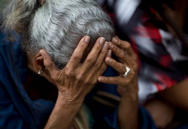 Una mujer se sujeta la cabeza con las manos mientras espera en una fila en el exterior de un supermercado para comprar comida, en Caracas, Venezuela. La escasez de alimentos en Venezuela es tal que decenas de miles de personas pasan hambre o están famélicas. El comprador medio pasa unas 35 horas al mes haciendo fila  