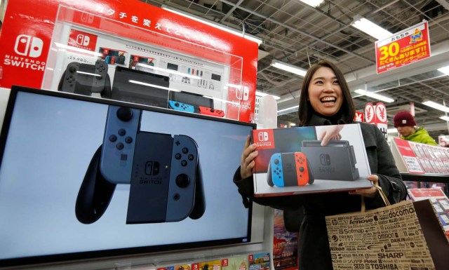 Nao Imoto smiles as she poses with her Nintendo Switch game console after buying it at an electronics store in Tokyo, Japan March 3, 2017.  REUTERS/Toru Hanai