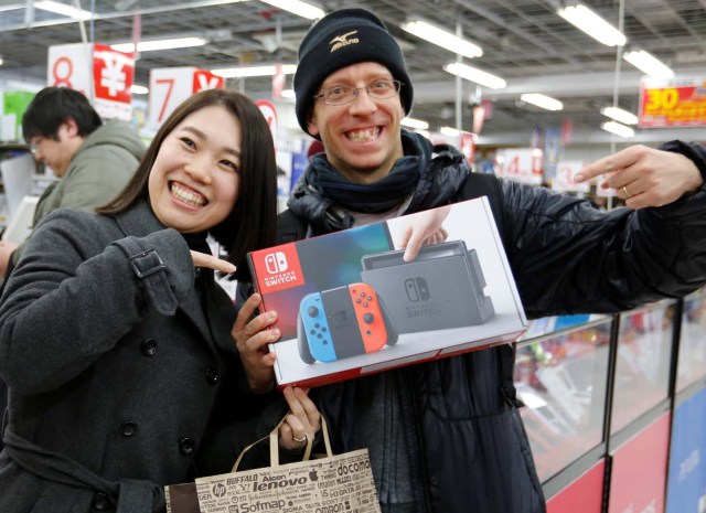 Nao Imoto (L) and her husband David Flores poses with their Nintendo Switch game console after buying it at an electronics store in Tokyo, Japan March 3, 2017. REUTERS/Toru Hanai