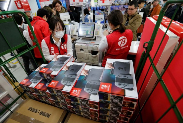 A sales staff takes a Nintendo Switch game console for a customer at an electronics store in Tokyo, Japan March 3, 2017. REUTERS/Toru Hanai