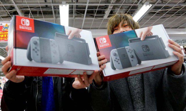 Customers pose with their Nintendo Switch game consoles after buying at an electronics store in Tokyo, Japan March 3, 2017.REUTERS/Toru Hanai