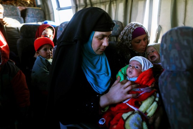 A woman, who just fled a village controled by Islamic State militants, holds her newborn baby as she sits inside a bus before heading to a camp at Hammam Ali, south of Mosul, Iraq February 22, 2017. REUTERS/Zohra Bensemra