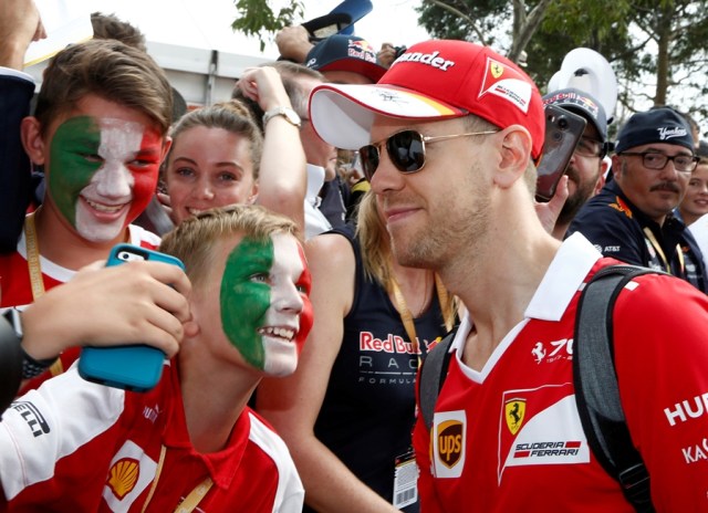 Formula One - F1 - Australian Grand Prix - Melbourne, Australia - 26/03/2017 Ferrari driver Sebastian Vettel of Germany poses with a fan as he arrives at the track. REUTERS/Brandon Malone