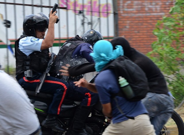 Students opposing Venezuelan President Nicolas Maduro scuffle with policemen on a motorcycle during a demonstration in San Cristobal, Venezuela on April 5, 2017. University students and police clashed Wednesday during a protest in the Venezuelan city of San Cristobal (western border with Colombia), with a balance of at least a dozen injured. / AFP PHOTO / George Castellanos