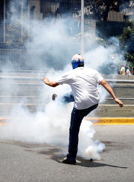 A demonstrator kicks a gas canister during an opposition rally in Caracas, Venezuela