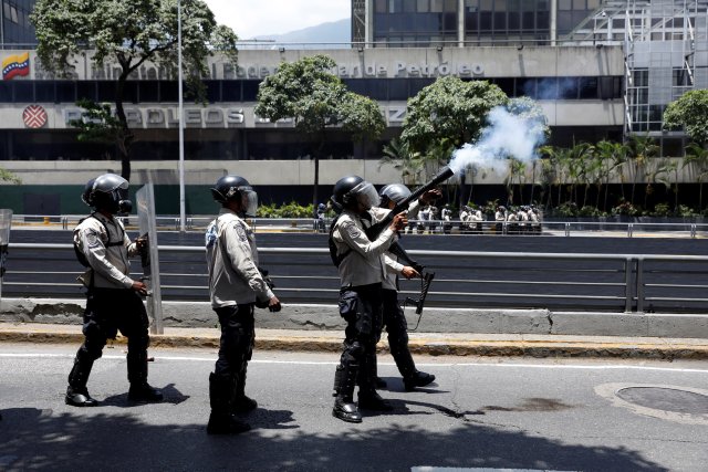 Riot police offcer fires a gas canister during an opposition rally in Caracas, Venezuela