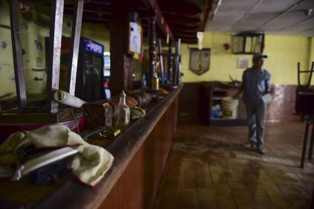 A man tidies up a restaurant in Caracas on April 20, 2017 a day after businesses were looted after demonstrations pro and against the government of Venezuelan President Nicolas Maduro. Venezuelan riot police fired tear gas Thursday at groups of protesters seeking to oust Maduro, who have vowed new mass marches after a day of deadly unrest. On the eve, hundreds of thousands of people fed up with food shortages and demanding elections joined protest marches in Caracas and several other cities while thousands of Maduro's supporters held a counter-rally in central Caracas.  / AFP PHOTO / Ronaldo SCHEMIDT