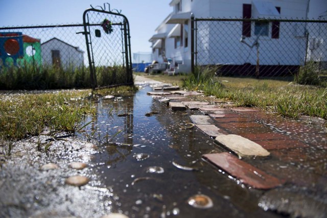 Sea water collects on the front walk way of a home in Tangier, Virginia, May 15, 2017, where climate change and rising sea levels threaten the inhabitants of the slowly sinking island. Now measuring 1.2 square miles, Tangier Island has lost two-thirds of its landmass since 1850. If nothing is done to stop the erosion, it may disappear completely in the next 40 years. / AFP PHOTO / JIM WATSON